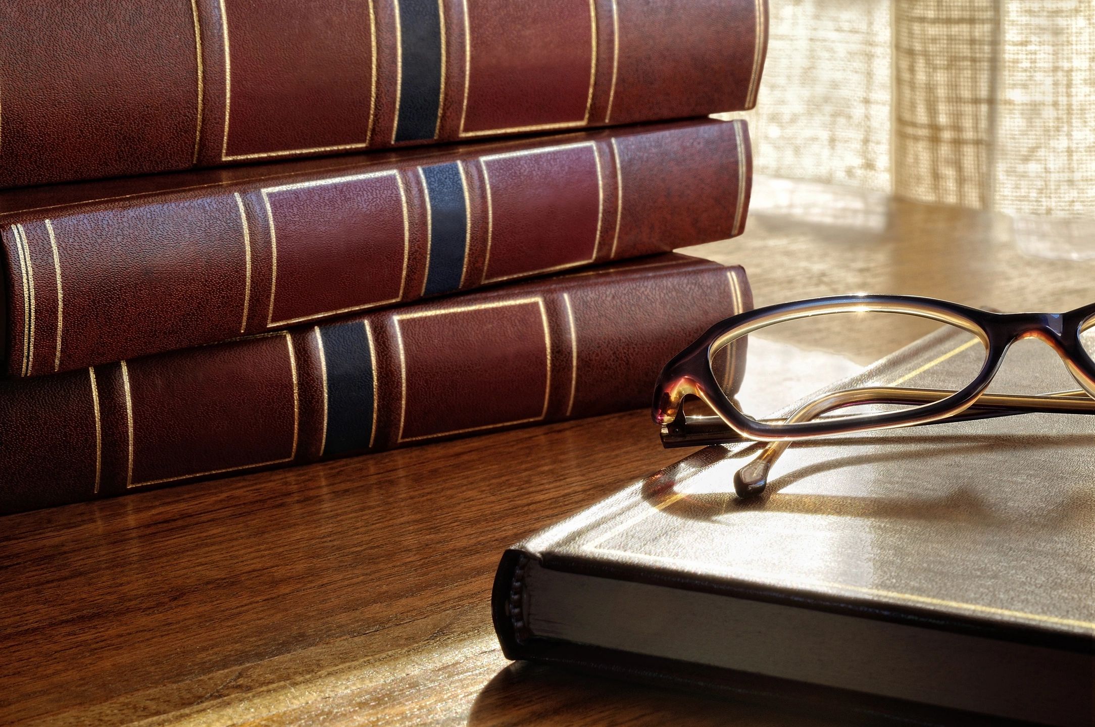 Stack Of Legal Books With Reading Glasses On A Wooden Desk Representing Jm Legacy Law’s Estate Planning And Probate Services.